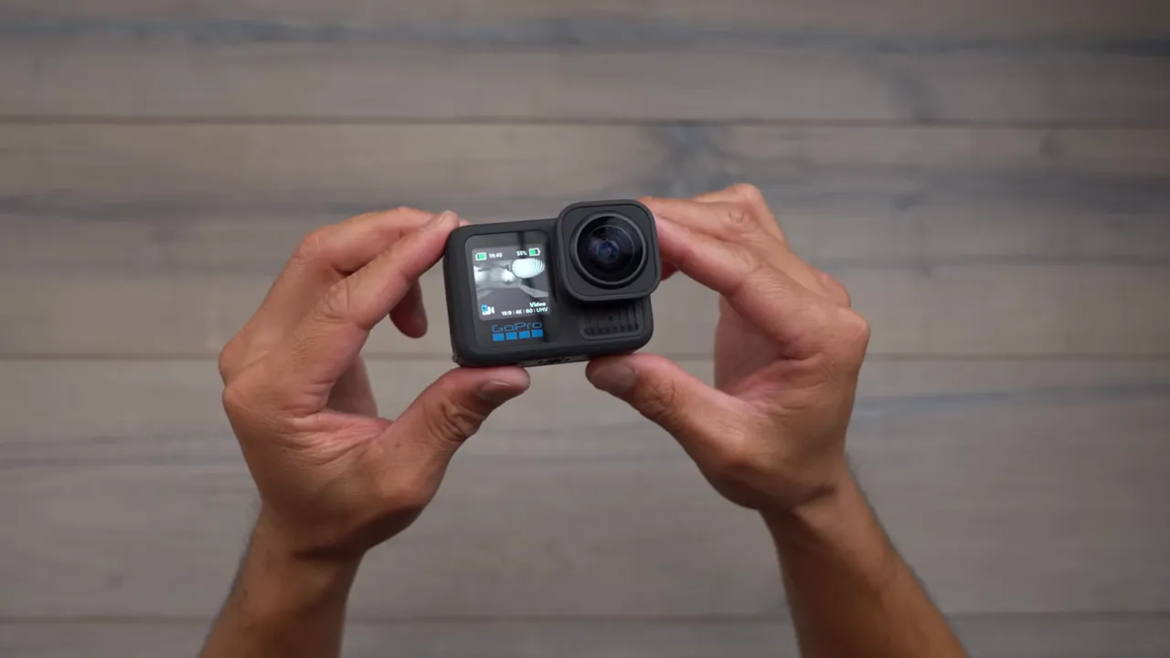 Hands holding an action camera showing the front lens and small front display