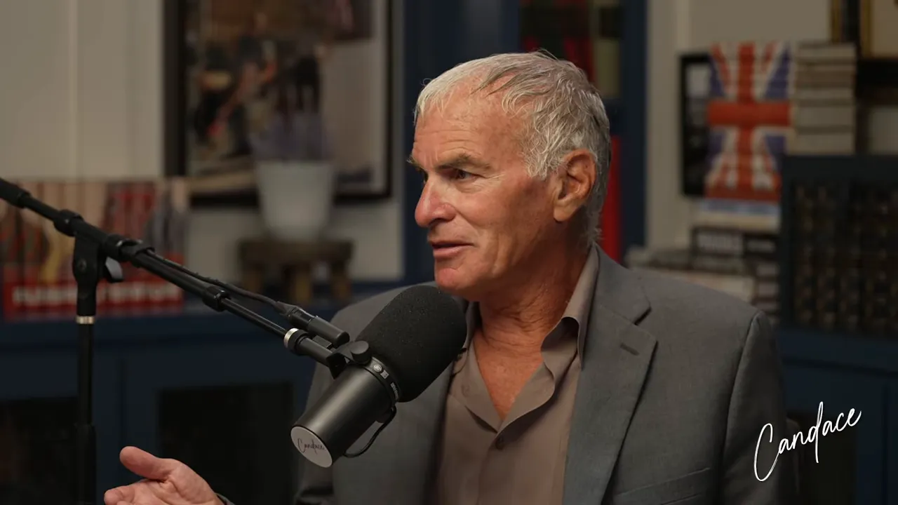 Podcast guest gesturing with one hand while speaking into a microphone in a studio