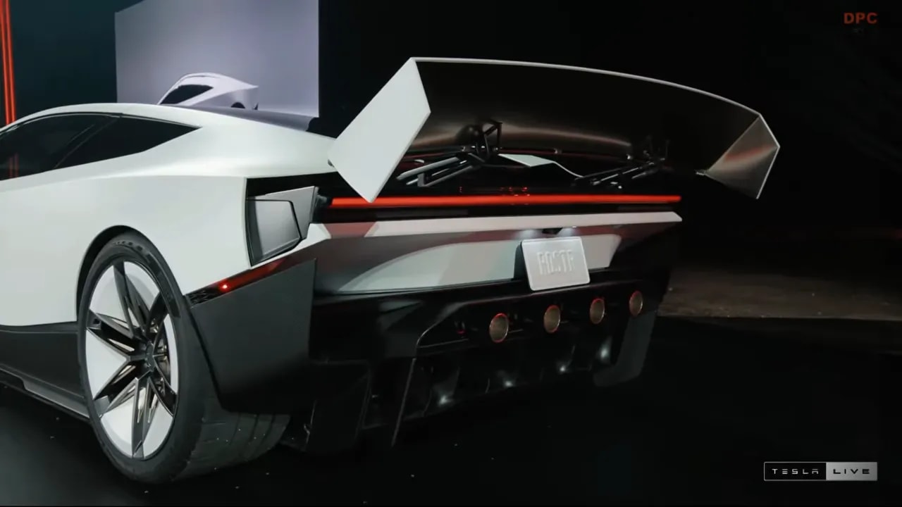 Rear three-quarter view of the Roadster with its rear wing raised above exposed hardware